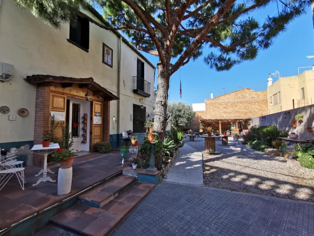 einen Innenhof mit einem Baum und einem Gebäude in der Unterkunft Mucha Masia Hostel Rural Urba in El Prat de Llobregat