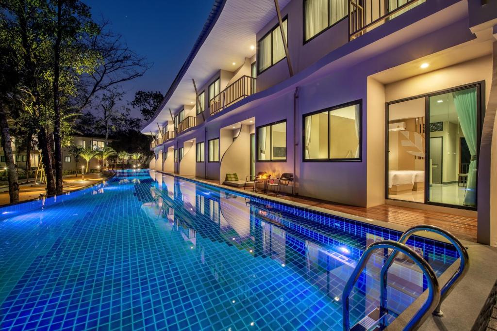 a swimming pool in front of a building at night at At Rice Resort in Nakhon Nayok