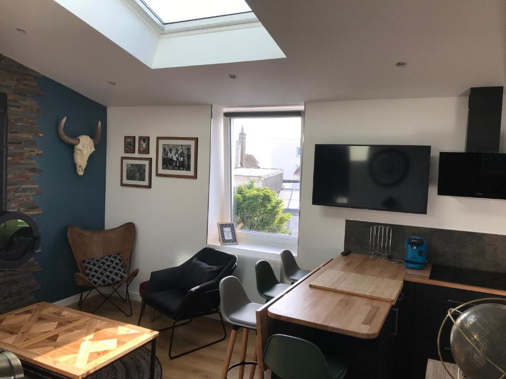 - un salon avec une table, des chaises et une télévision dans l'établissement LE FARNIENTE AU BORD DE MER, à Wimereux