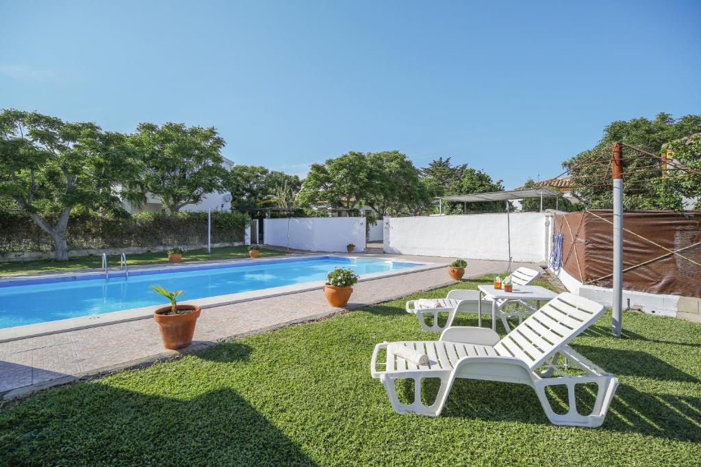 een tuin met twee witte stoelen en een zwembad bij Los paraisos 1 in Conil de la Frontera