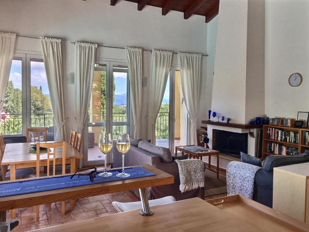 a living room with a couch and a table with wine glasses at Gastouri Villa Pascalia with heated pool in October and views in Achílleion