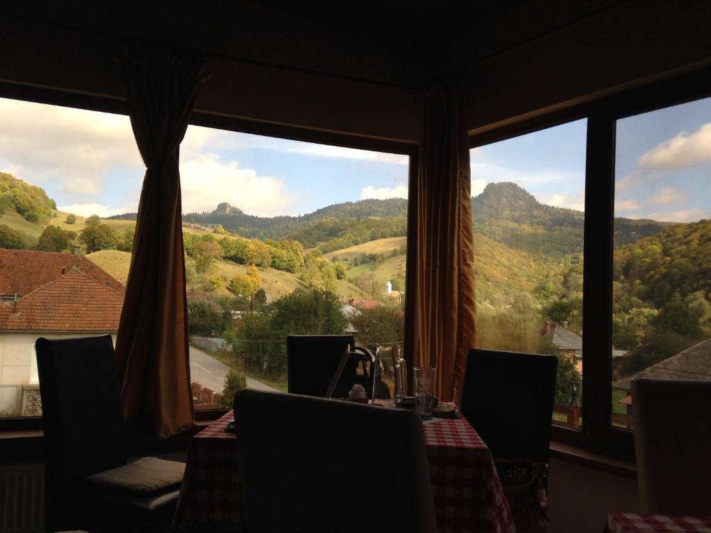 a dining room with a table and a view of mountains at Pensiunea Casa Motilor in Bucium