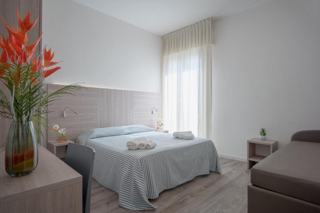 a white bedroom with a bed and a vase of flowers at Hotel San Francisco in Lido di Savio