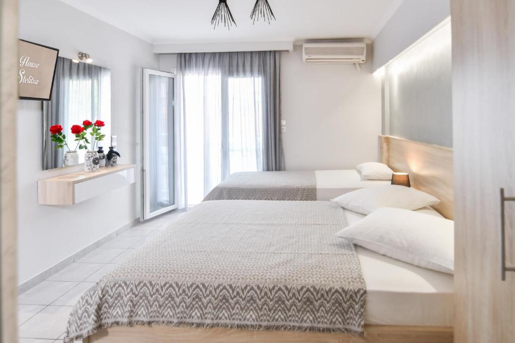 a white bedroom with two beds and a window at House Stelitsa in Sarti