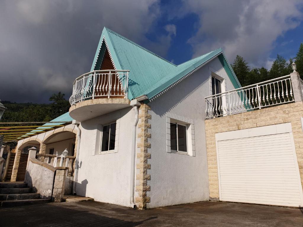 a white house with a blue roof and a garage at Le paradis du Cap des Camélias in Saint-Leu
