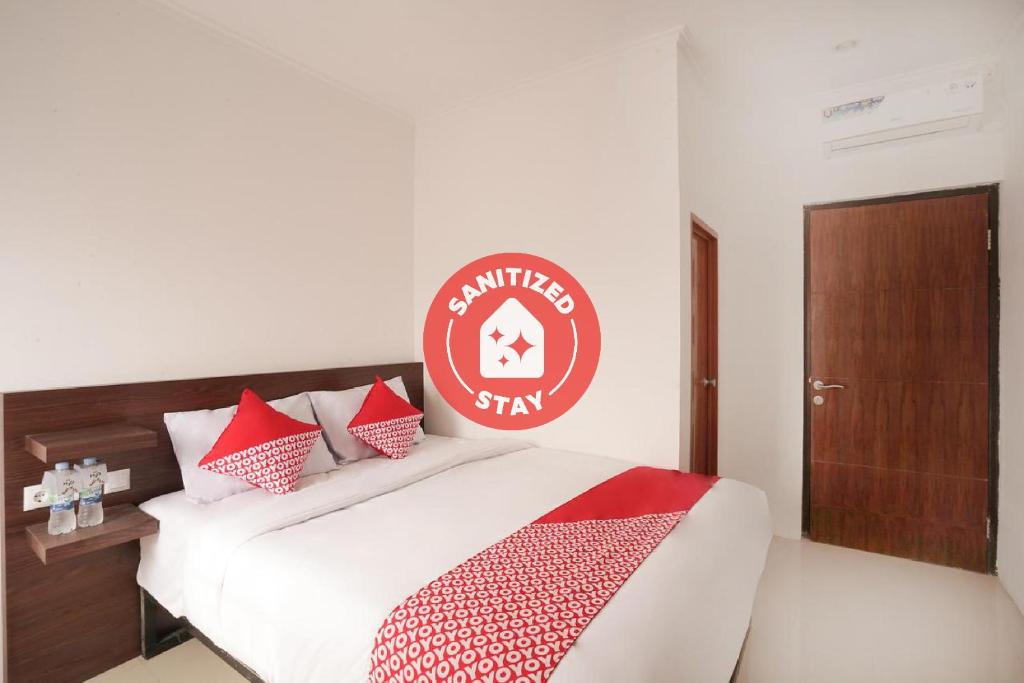 Un dormitorio con una cama blanca con almohadas rojas y blancas en Super OYO 2183 Cibeureum Residence, en Bandung