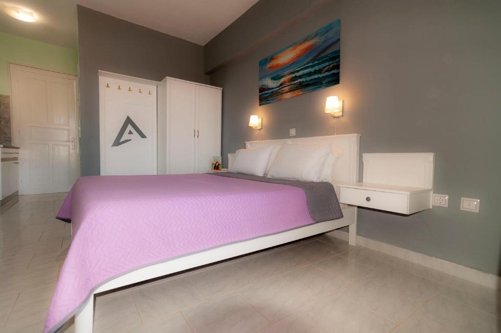 a bedroom with a large bed with a purple blanket at Alpha Studios in Arkasa