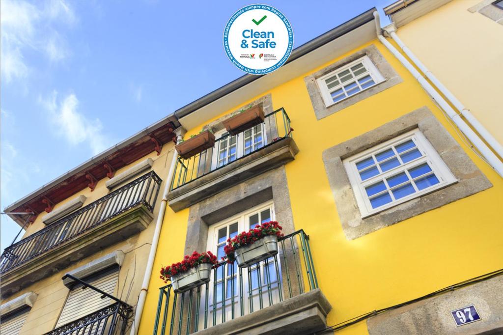 a yellow building with windows and a sign on it at Historical Center - Taipas Apartments in Porto