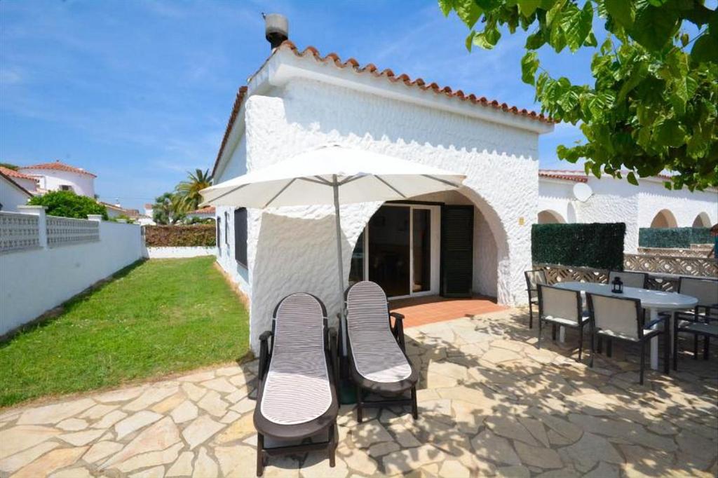 Un patio con una mesa y sillas y una sombrilla. en Casas Montgrí, en Empuriabrava