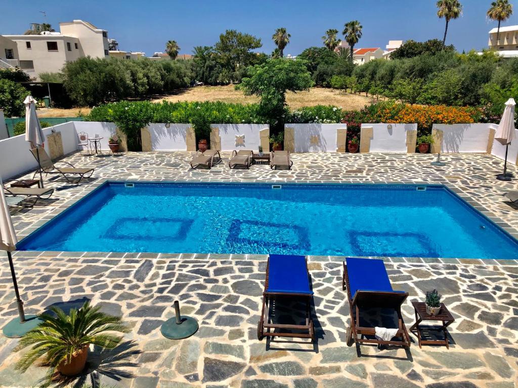 a patio area with chairs, a table, and a pool at Angela Holiday Apartments in Paphos City