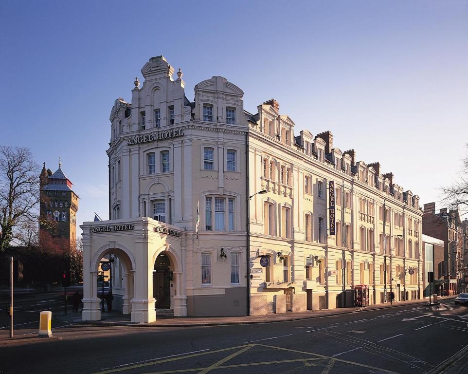 een groot wit gebouw met een klokkentoren op een straat bij The Angel Hotel in Cardiff