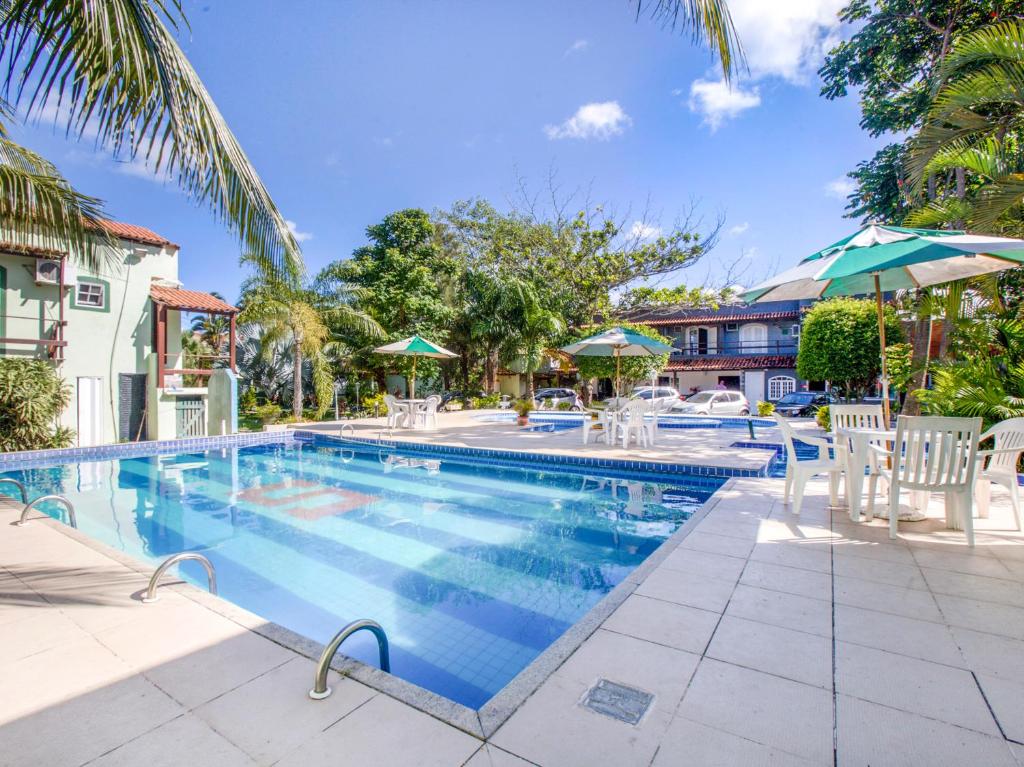 una piscina con sillas y sombrillas en un hotel en OYO Pousada Recanto Shangrilá, Cabo Frio, en Cabo Frío