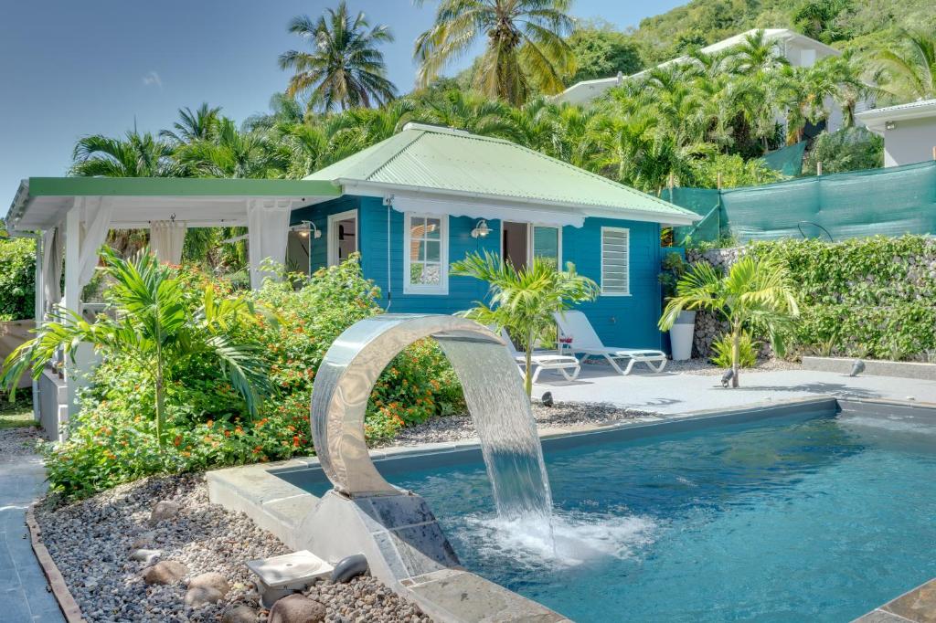 a swimming pool with a water fountain in front of a house at Complexe de deux bungalows de standing in Case-Pilote