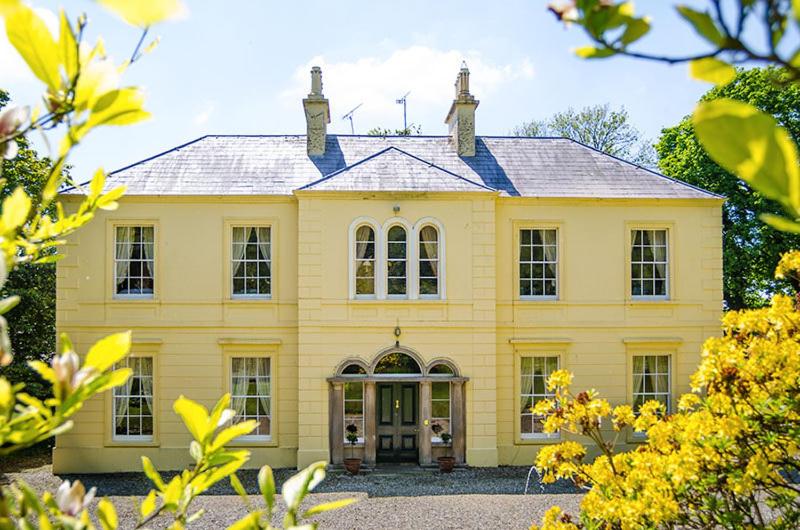 ein großes gelbes Haus mit großer Eingangstür in der Unterkunft Nutgrove House Luxury B&B in Seaforde