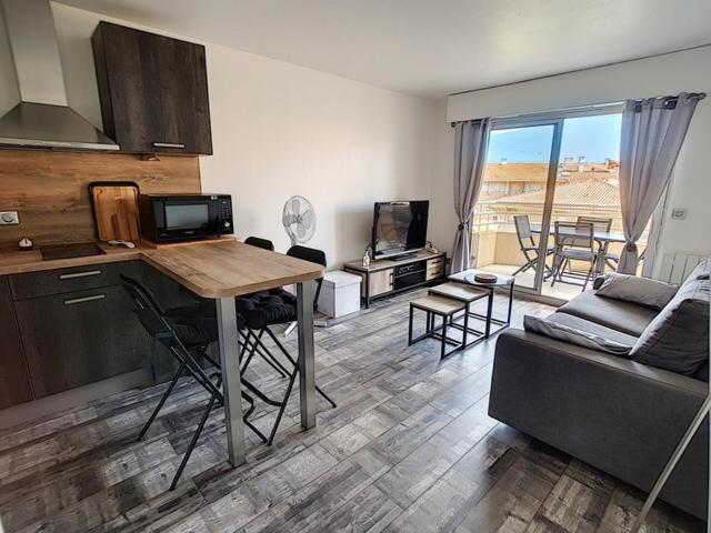 uma cozinha e sala de estar com uma mesa e um sofá em APPART JL Port Fréjus em Fréjus