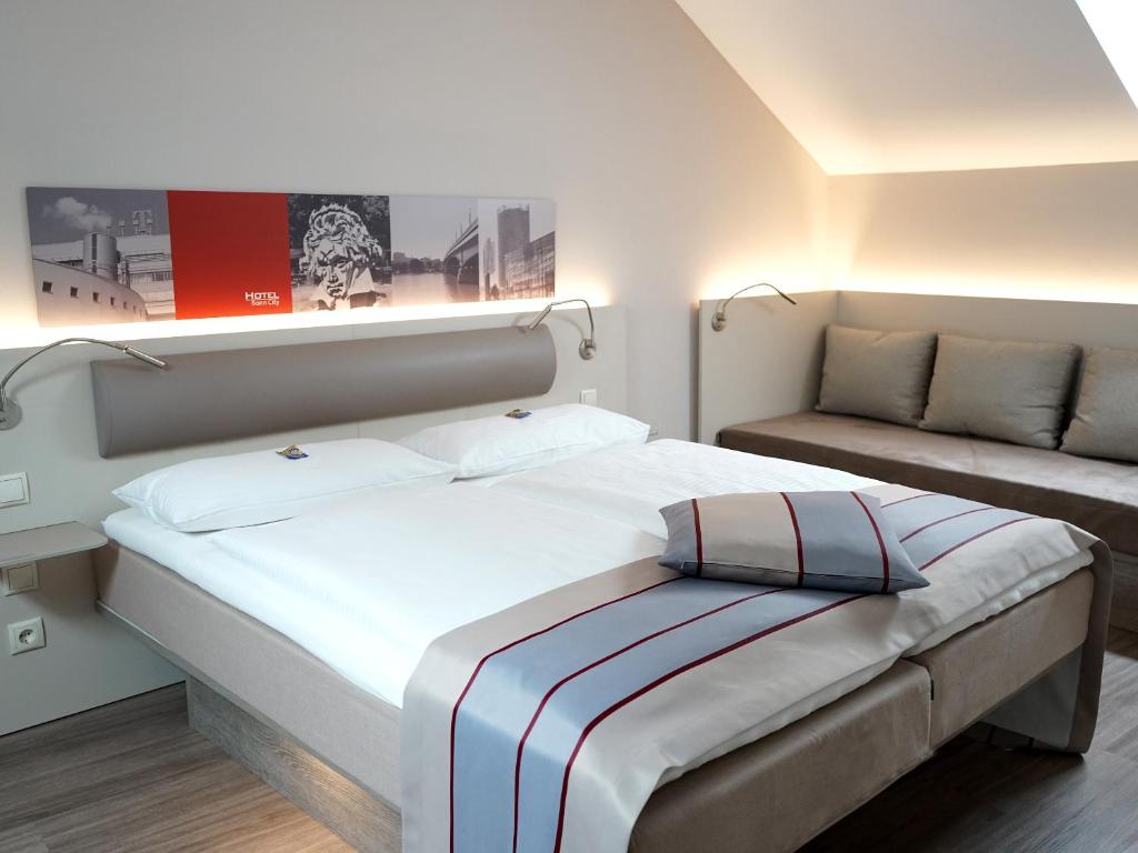 a bedroom with a large bed and a couch at Hotel Bonn City in Bonn