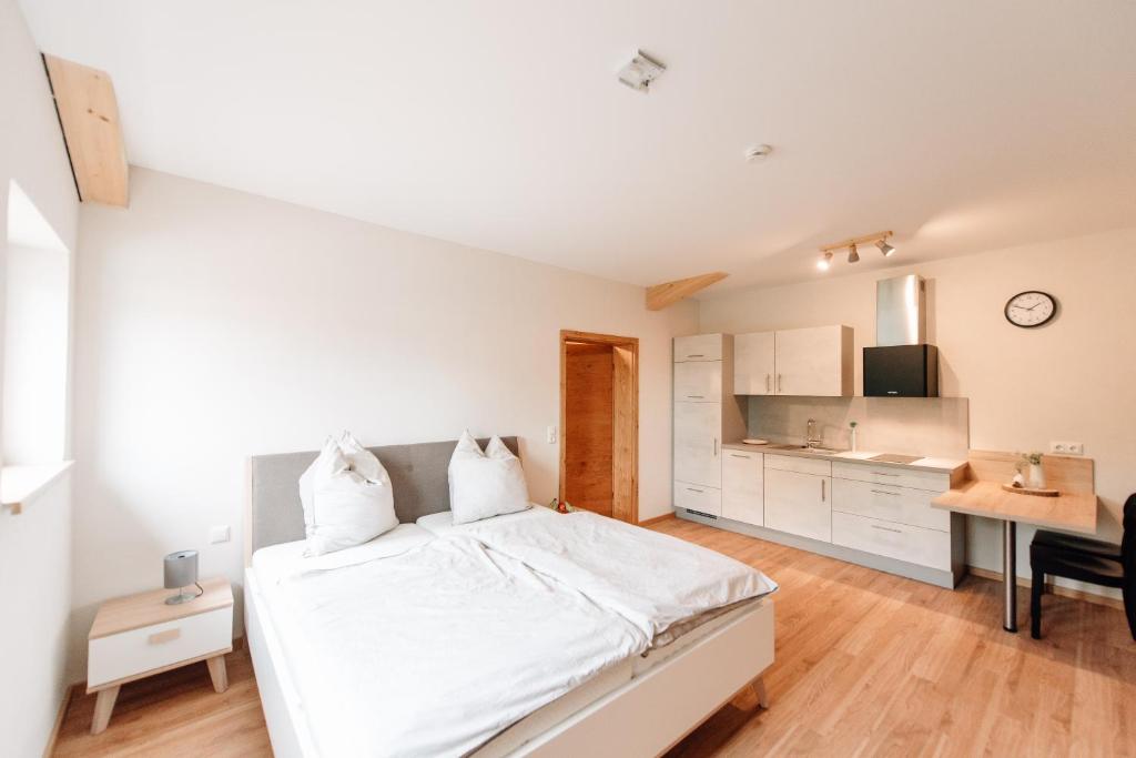 a white bedroom with a bed and a desk at Wallochny-Hof in Marktbreit