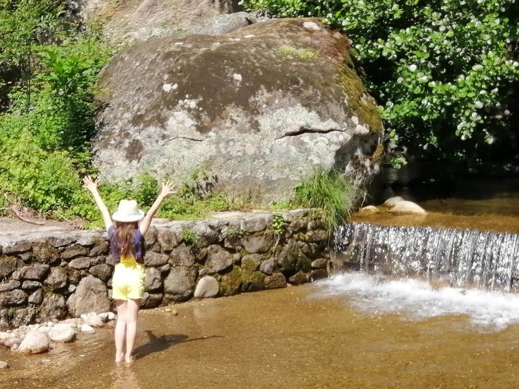 una mujer parada en el agua frente a una cascada en el Sotanillo en Valverde de la Vera
