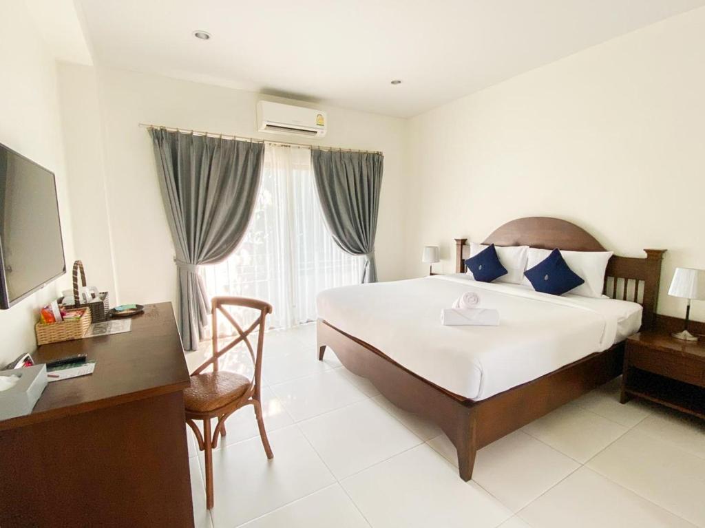 um quarto de hotel com uma cama, uma secretária e uma televisão em Koranaree Courtyard Boutique Hotel em Nakhon Ratchasima