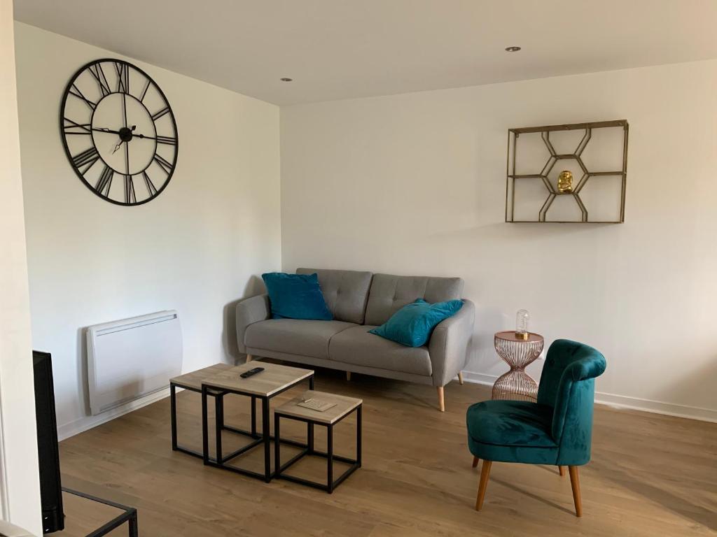 a living room with a couch and a clock on the wall at Appartement au cœur d’Auray au 1er étage in Auray