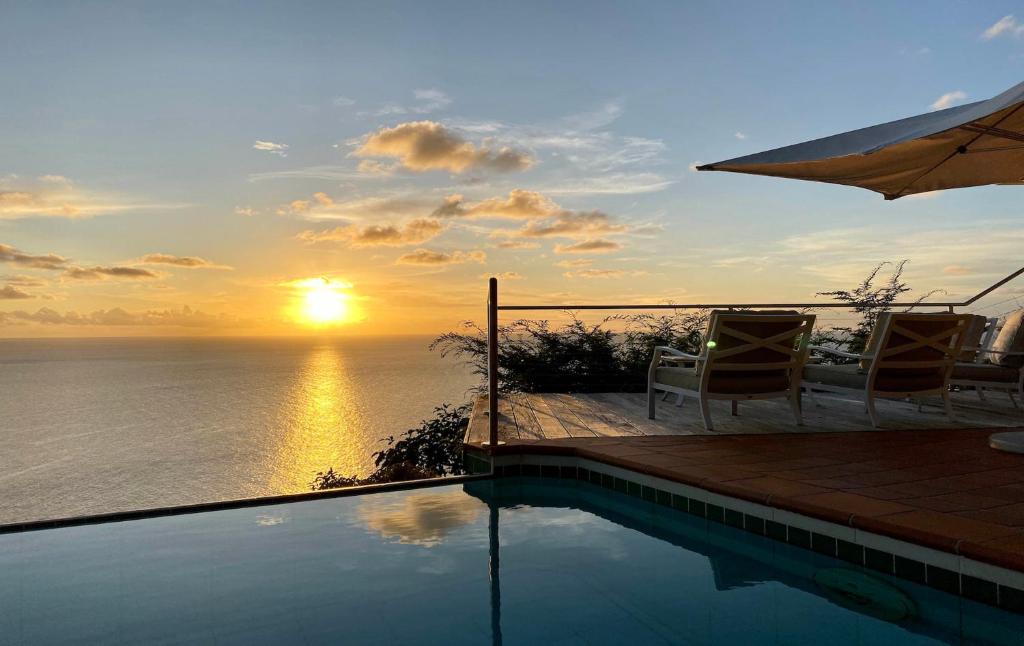 a swimming pool with a sunset over the ocean at Dream Villa Corossol 783 in Saint Barthelemy