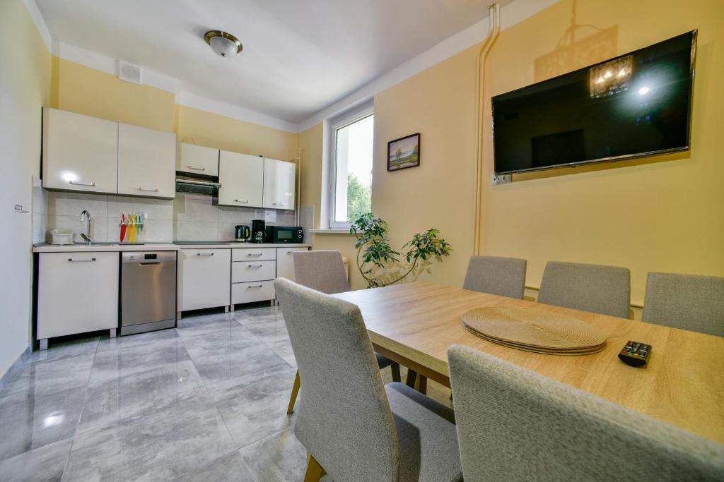 a kitchen and dining room with a wooden table and chairs at Apartament u Ewy w Kołobrzegu - Podczele in Kołobrzeg