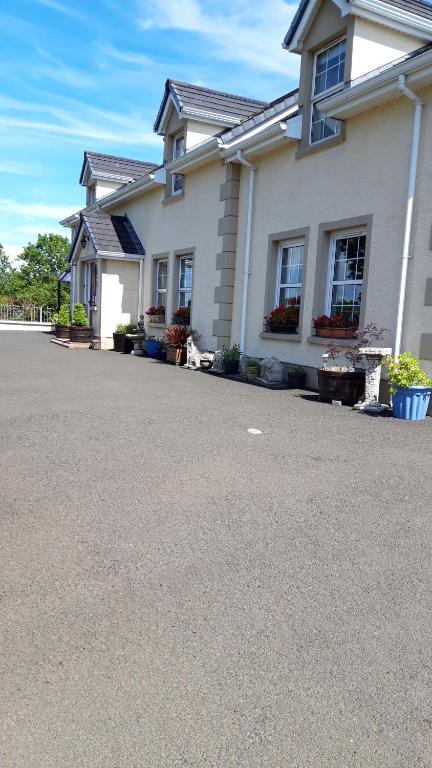 Biały dom z psem siedzącym przed nim w obiekcie Lurig View B&B Glenariffe w mieście Glenariff