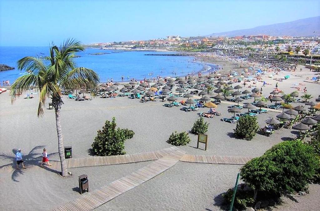 una spiaggia con molti ombrelloni e persone sopra di Guest House Beach & Fun a Playa de las Americas