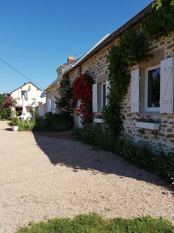 ein Backsteinhaus mit Blumen an der Seite in der Unterkunft Le Gîte De L'Ouche Charlot in Maux