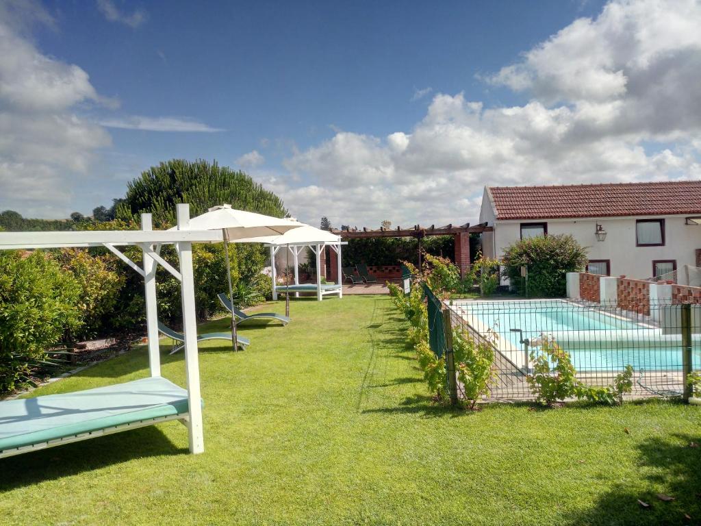 um quintal com uma piscina e um guarda-sol em Casa Adega Do Mosteiro - Turismo Rural nas Caldas da Rainha