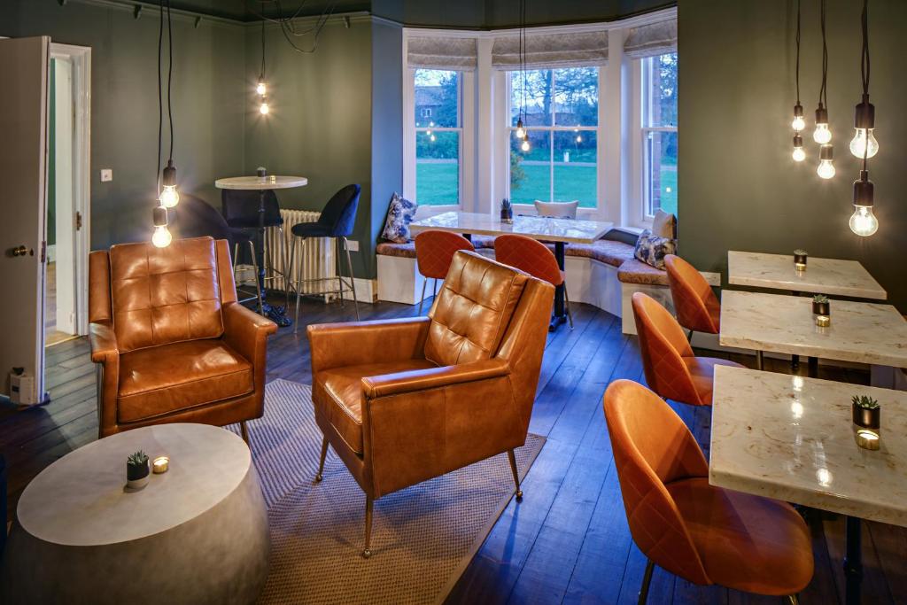 a restaurant with leather chairs and tables and windows at Blakeney House in Blakeney
