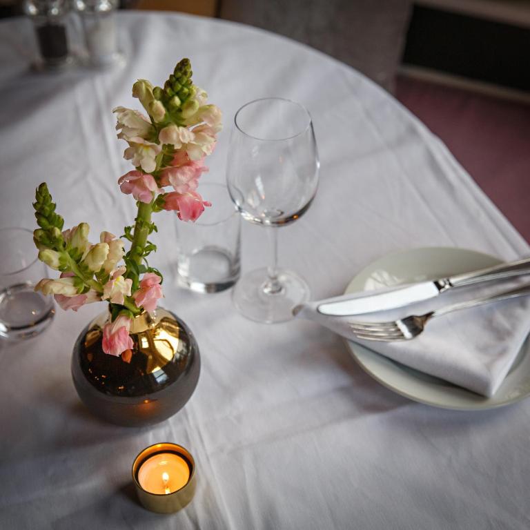 a table with a vase with flowers and a candle at Blakeney House in Blakeney