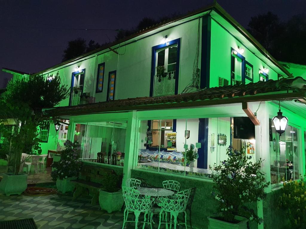 zielony budynek ze stołami i krzesłami w nocy w obiekcie Pousada das Hortensias w mieście Conservatória
