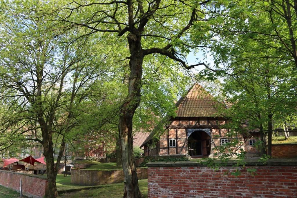 an old house with a brick wall and trees at Biohotel WildLand Natural Resort in Hornbostel