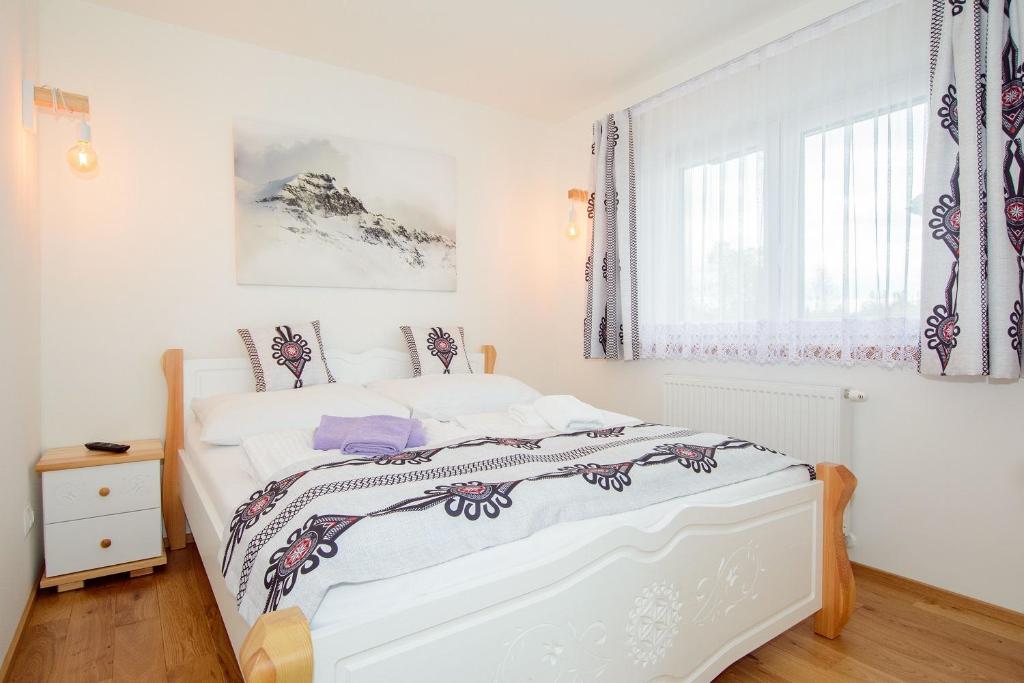a white bed in a white bedroom with a window at Apartamenty Toporowe Domki in Witów
