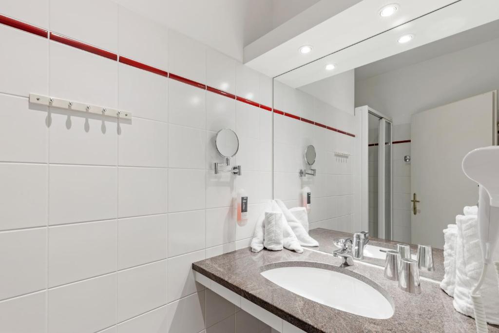 biała łazienka z umywalką i lustrem w obiekcie GAL Apartments Vienna w Wiedniu