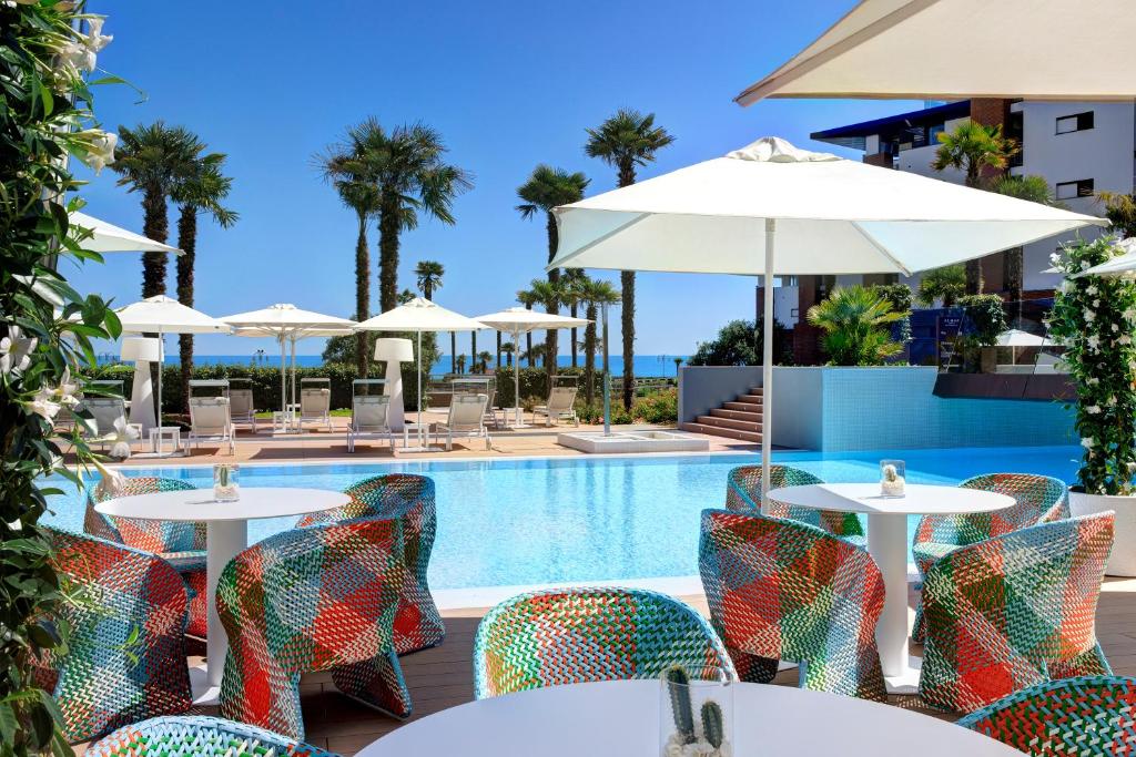 a view of the pool at the resort with tables and umbrellas at Almar Jesolo Resort & Spa in Lido di Jesolo