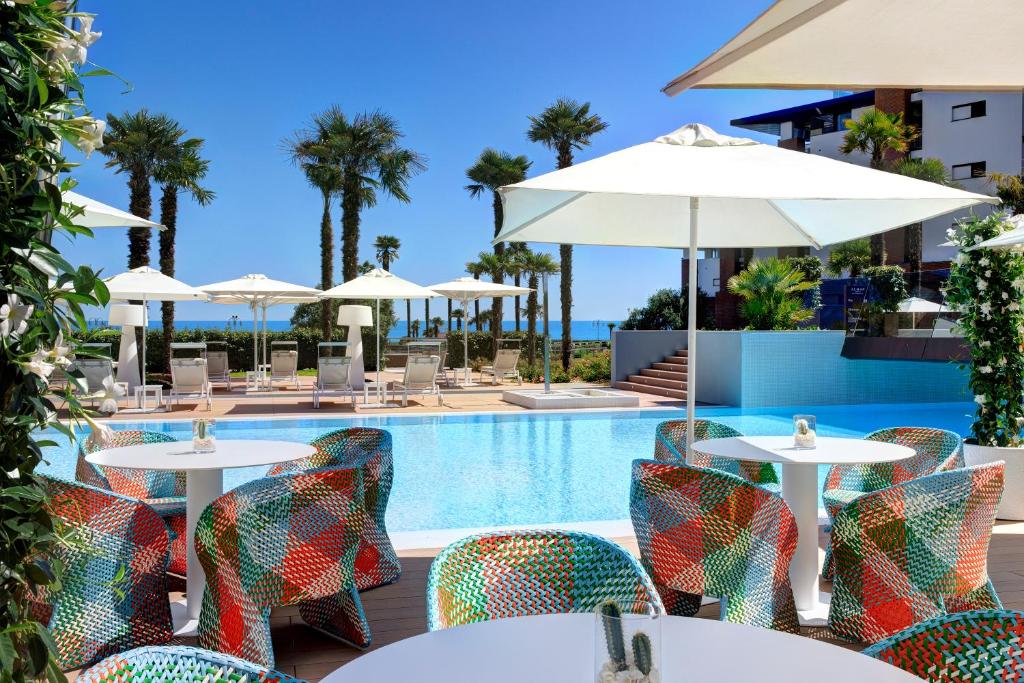 een uitzicht op het zwembad van het resort met tafels en parasols bij Almar Jesolo Resort & Spa in Lido di Jesolo