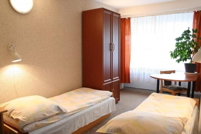 een slaapkamer met 2 bedden, een tafel en een raam bij Hotel Biała Gwiazda in Krakau