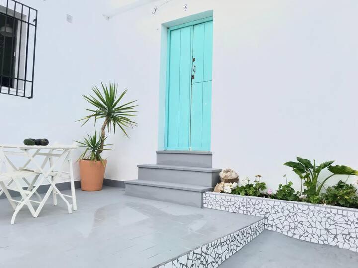 a white house with a blue door and some plants at Casa ALBAYZÍN in Salobreña