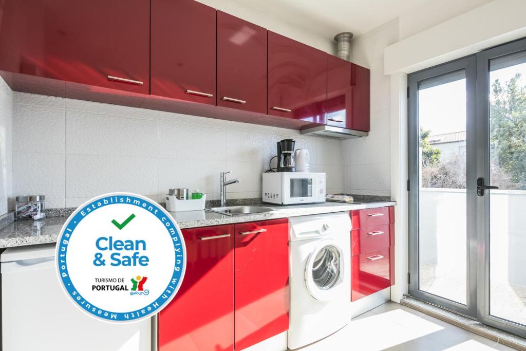 uma cozinha com armários vermelhos e uma máquina de lavar roupa em Apartamento À Francos Balcony no Porto