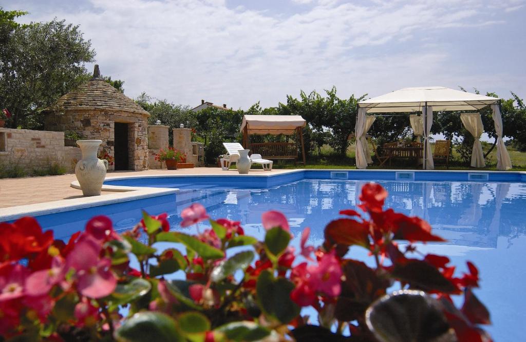 a swimming pool with a gazebo and red flowers at Apartments Ivan & Tina in Kanfanar