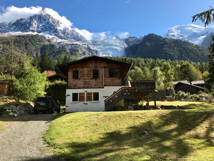 une maison sur une colline avec des montagnes en arrière-plan dans l'établissement Chalet in green, sunny and quite spot 5’ from center, à Chamonix-Mont-Blanc