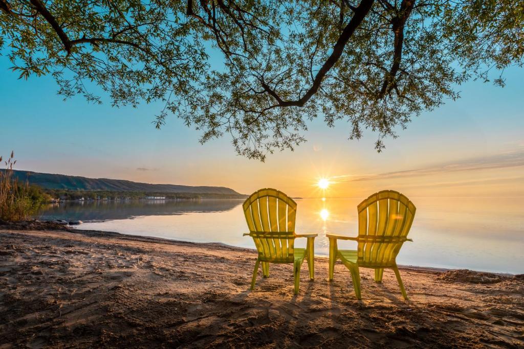 two yellow chairs sitting on a beach with the sunset at Boutique Suite #7 in Blue Mountains