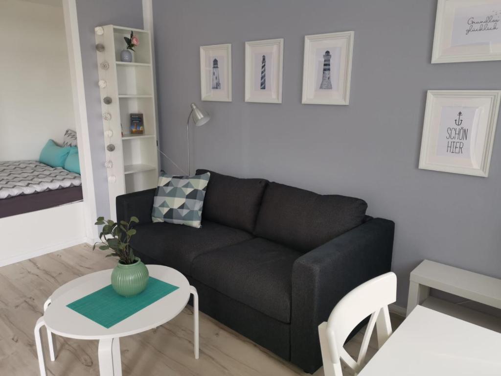 ein Wohnzimmer mit einem schwarzen Sofa und einem Tisch in der Unterkunft City-Apartment Perle in Bremerhaven