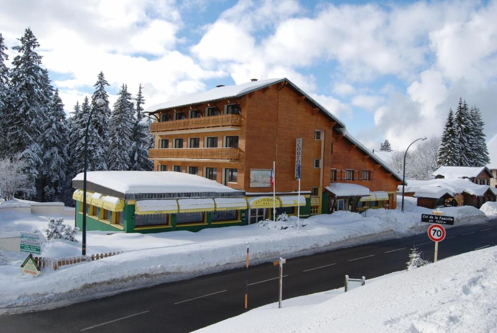 ein Gebäude im Schnee mit einem Bus vor der Tür in der Unterkunft Hôtel De La Couronne in Mijoux