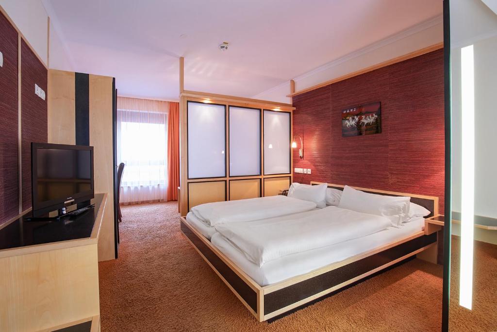 a bedroom with a bed and a flat screen tv at Bavaria Lifestyle Hotel in Altötting