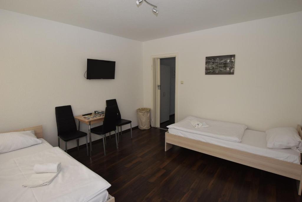 Habitación con 2 camas y mesa con sillas. en Apartment Wangen, en Stuttgart