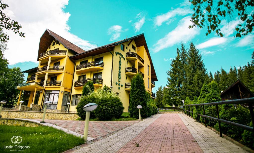 a yellow house with a brick walkway in front of it at Pension Vanatorul in Vatra Dornei