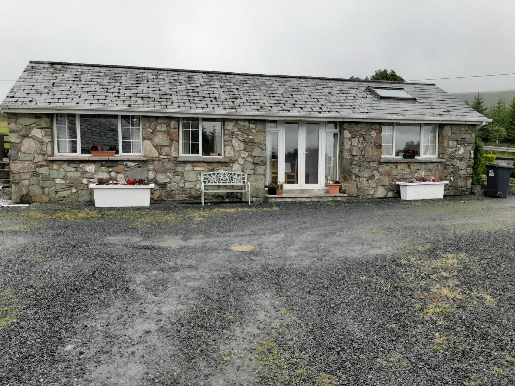 a stone house with a bench in front of it at The Lodge guesthouse in Brittas